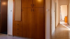 A bedroom with a large bed, wooden wardrobe, and a hallway leading to another room. - Adonis Villa (Pegeia)
