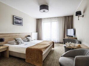 A hotel room with a bed, bedside table, lamp, TV, and a chair. - Mercure Wiazowna Brant  (Wiazowna)