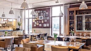 A restaurant with multiple tables, chairs, and hanging pendant lights.