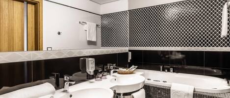 Un baño moderno con dos lavamanos, una bañera y un espejo.