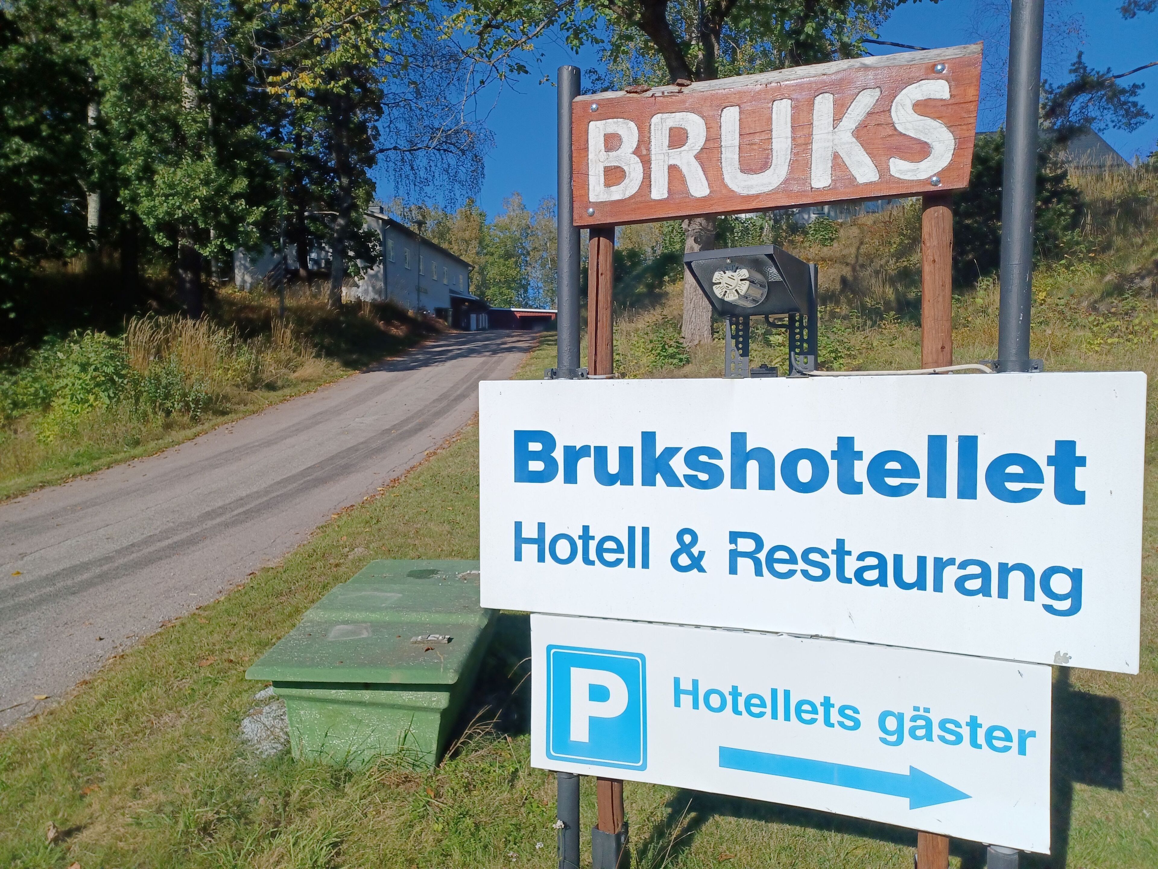 A sign for Bruksshotellet, indicating a hotel and restaurant with a parking area.