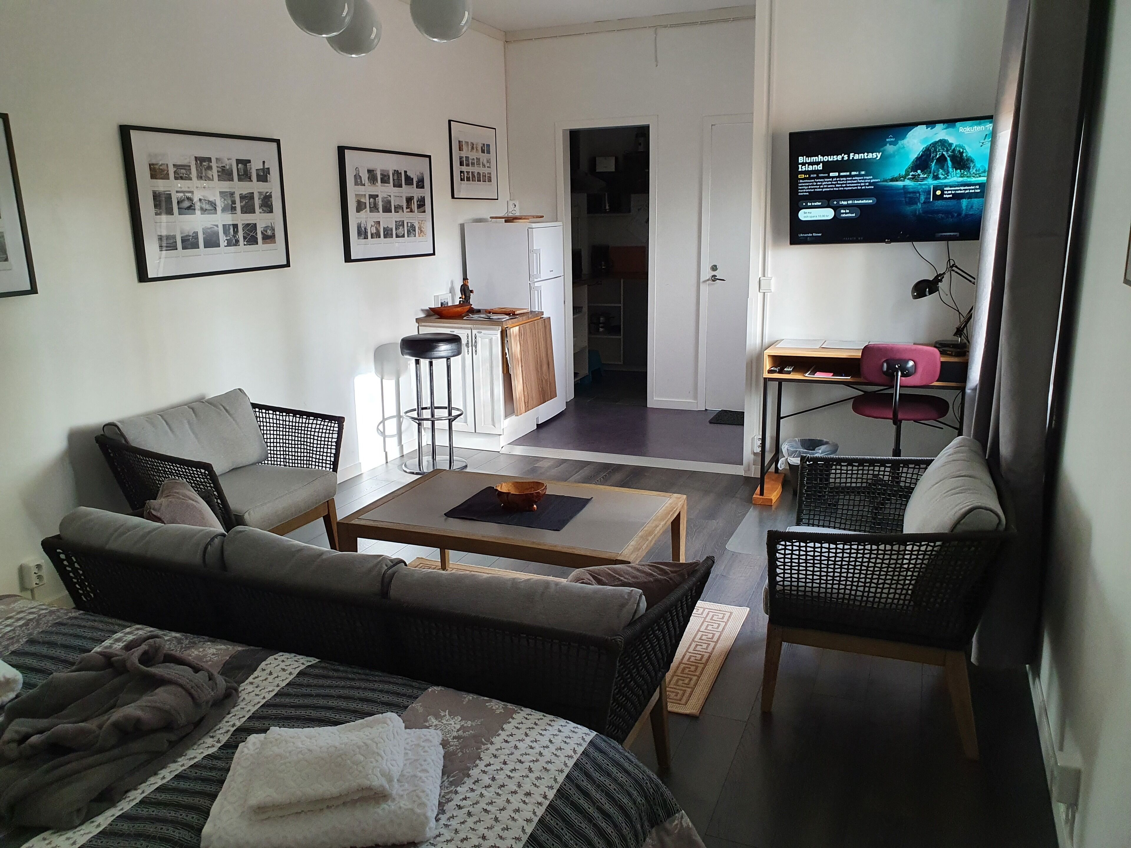 Una sala de estar moderna con sofá, mesa de centro y televisor mostrando 'Plumhouse’s Fantasy Island'.