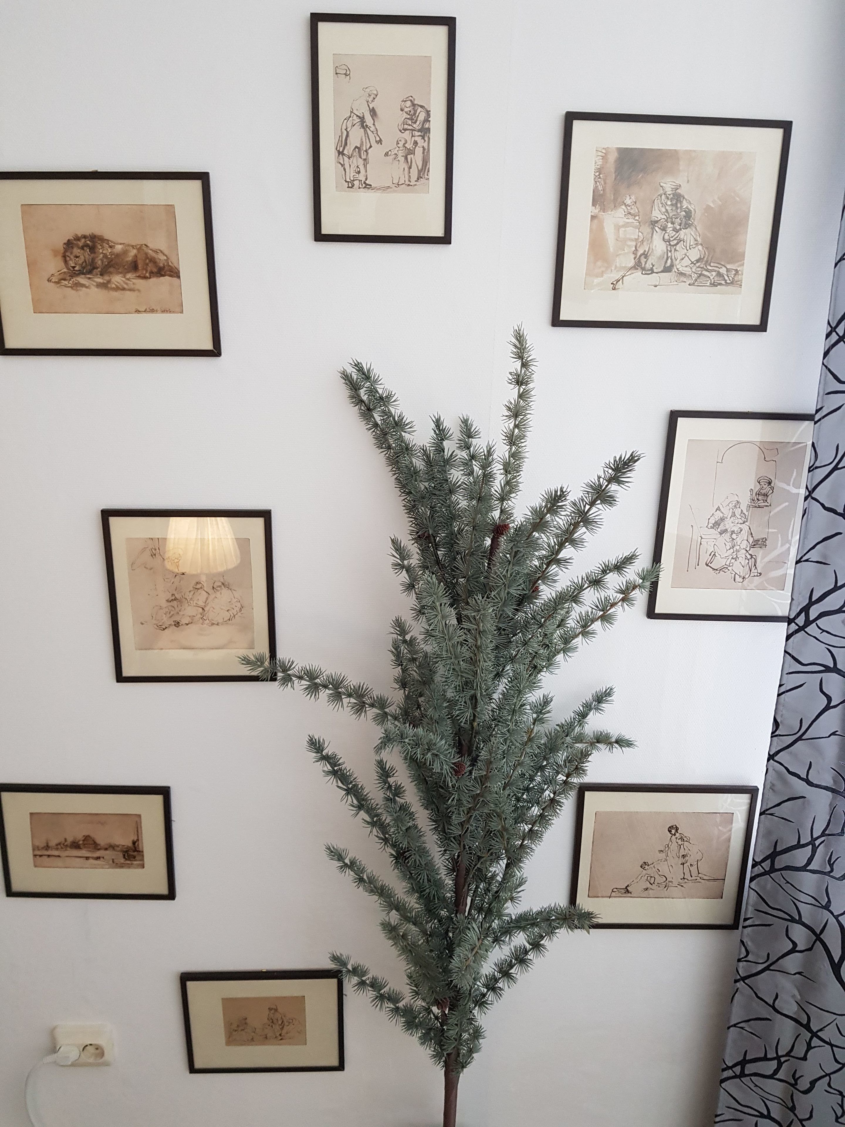 A wall with framed artwork and a central artificial tree.