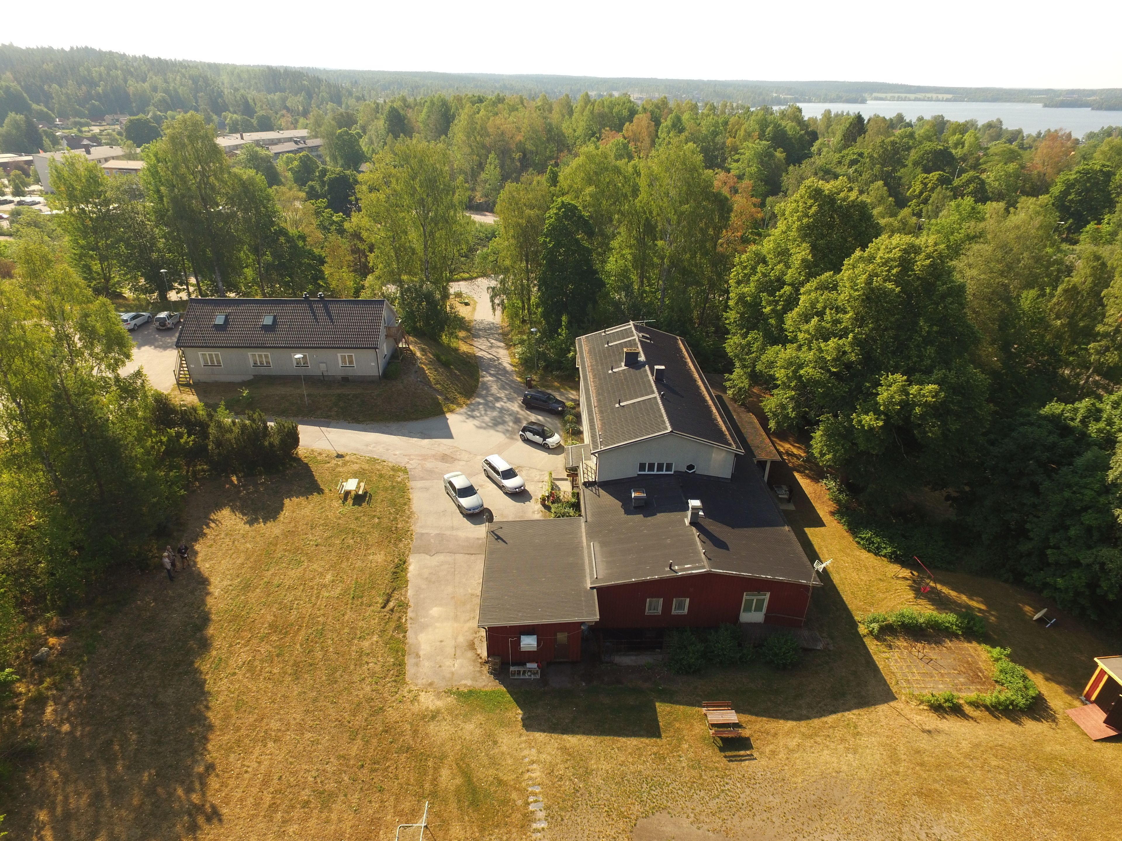 Vue aérienne d’un quartier résidentiel avec des maisons, un parking et un paysage boisé.