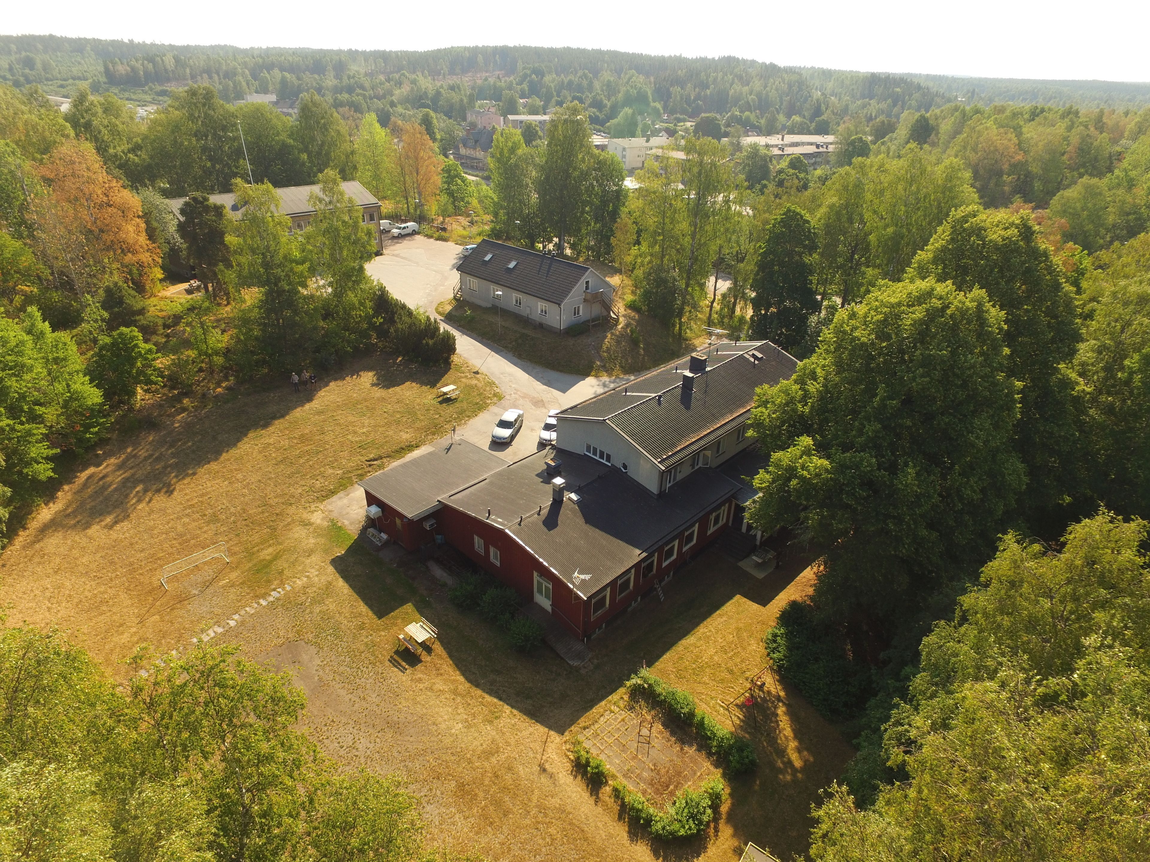An aerial view of a residential area with a large house, a smaller building, and a parking area.