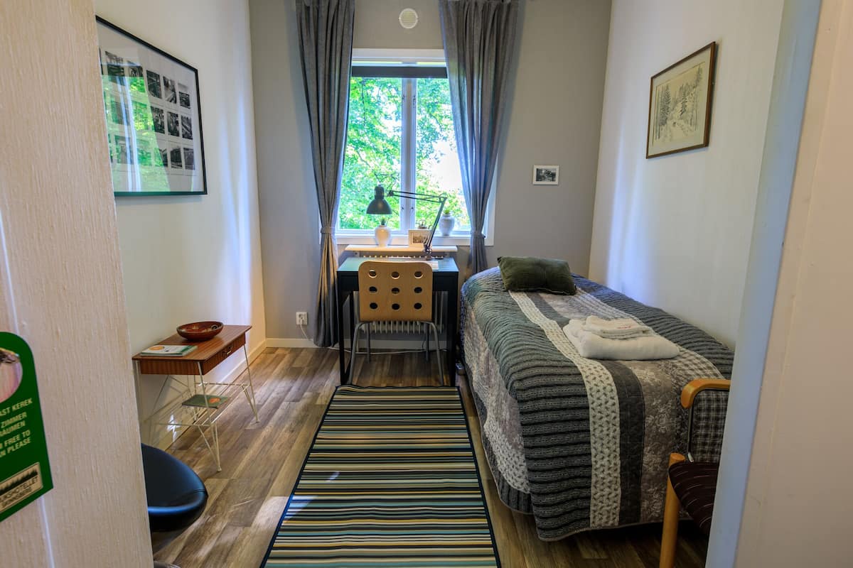 Ein kleines Zimmer mit einem Bett, einem Schreibtisch und einem Stuhl.
