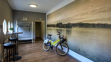 Una habitación con suelo de madera, una bicicleta, un perchero de pared y una puerta que da a otra estancia.