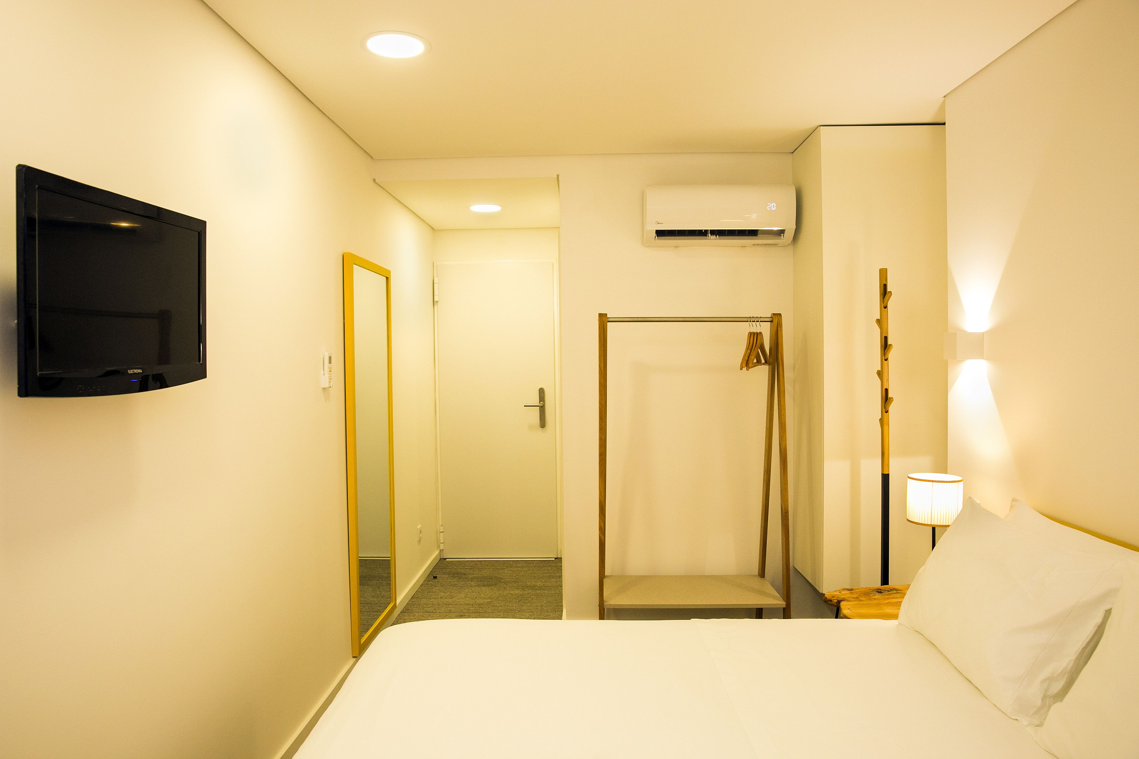 Une chambre d’hôtel équipée d’un lit, d’une télévision, d’une douche et d’un climatiseur fixé au mur.