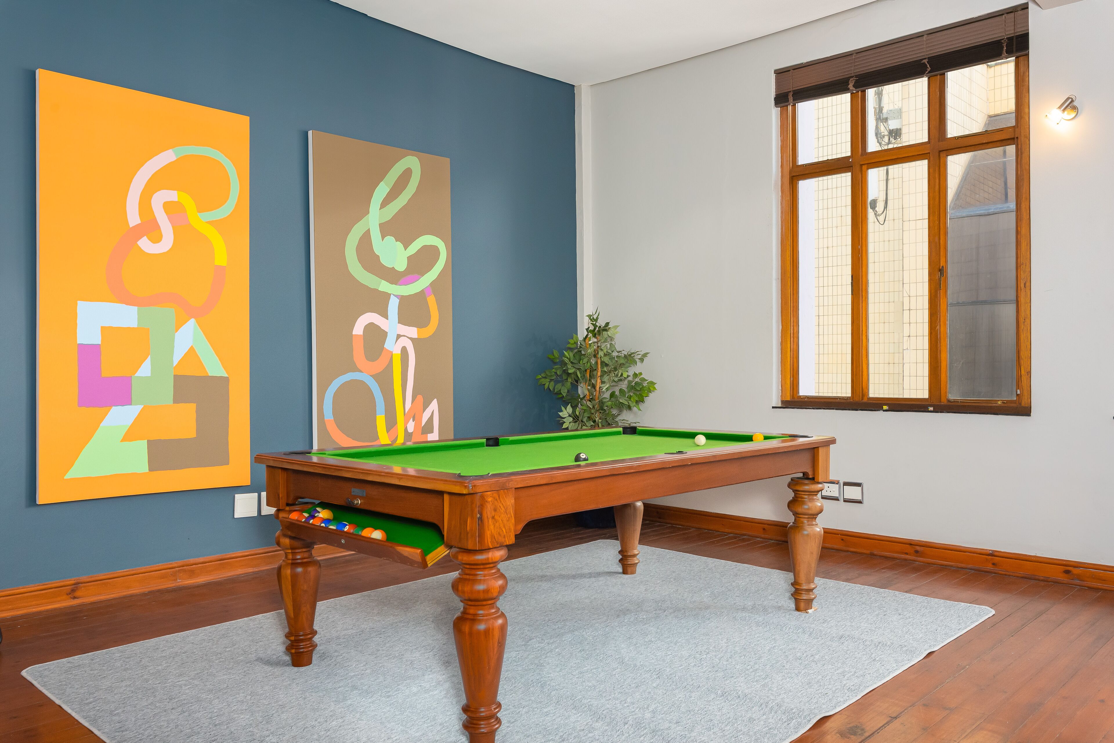 A pool table in a room with blue walls and a window.