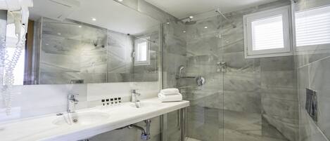 Une salle de bain moderne avec un meuble-lavabo en marbre, une cabine de douche en verre et un grand miroir.