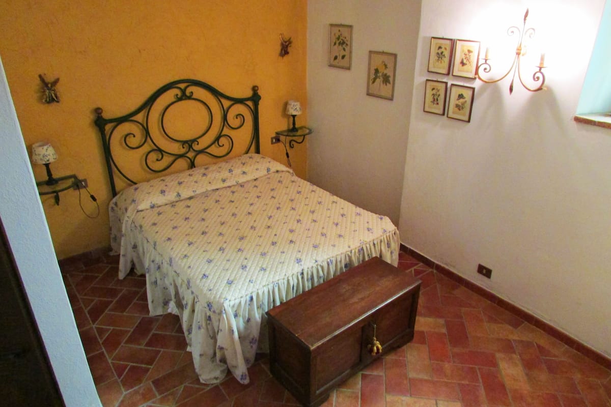 A bedroom with a bed, a nightstand, a dresser, and a wall with framed pictures.