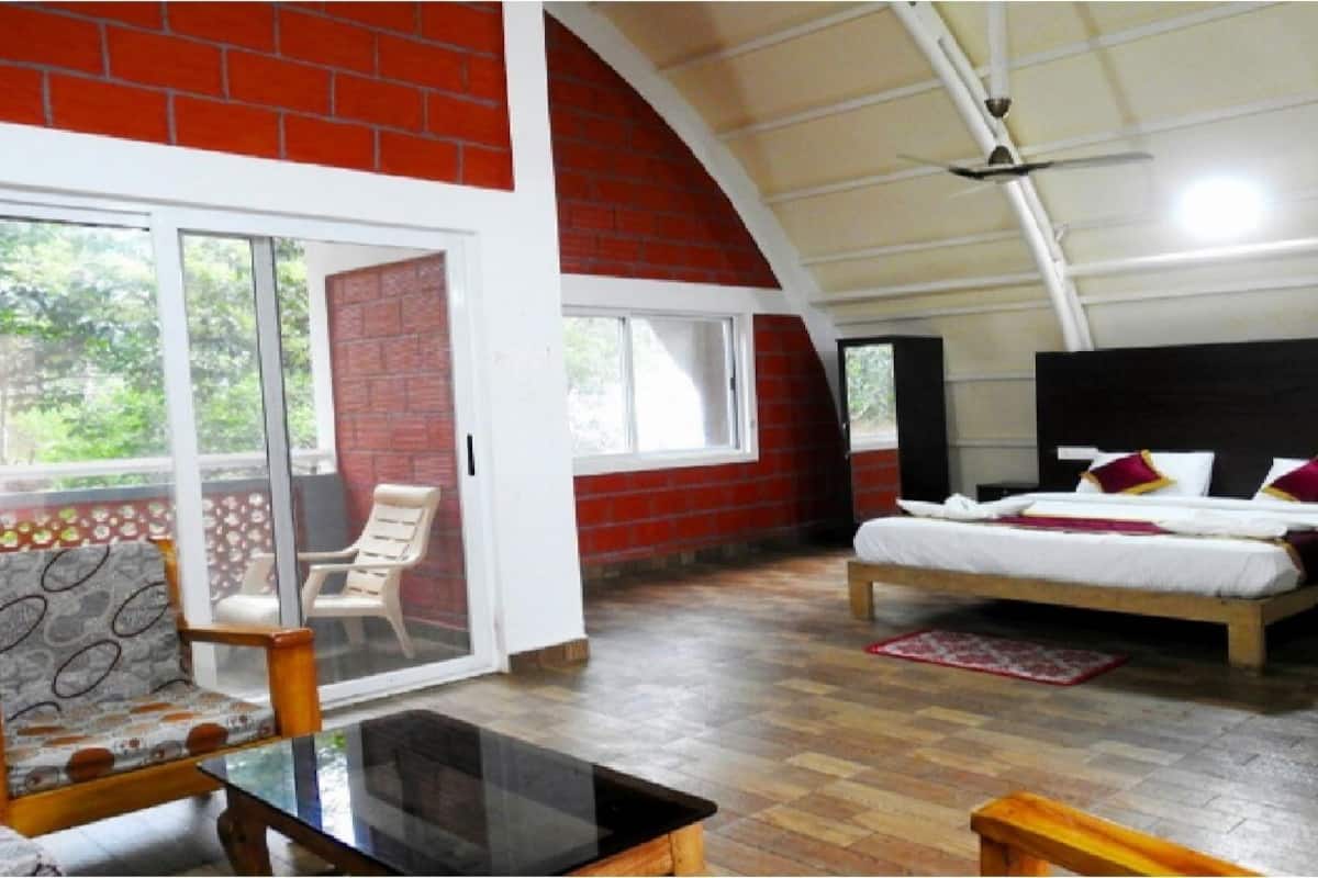 A bedroom with a bed, a chair, and a glass table.