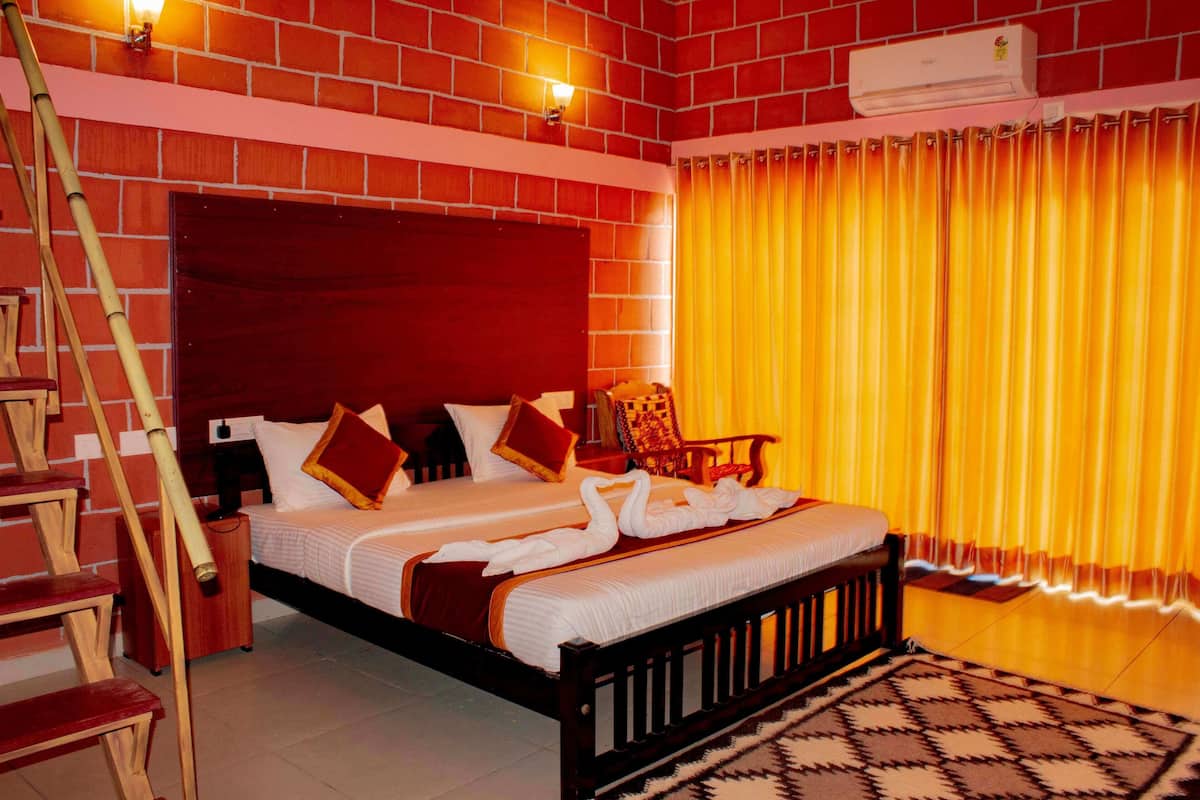 A hotel room with a brick wall, a wooden bed with white bedding, a wooden headboard, a wooden chair, a staircase, and a patterned rug.