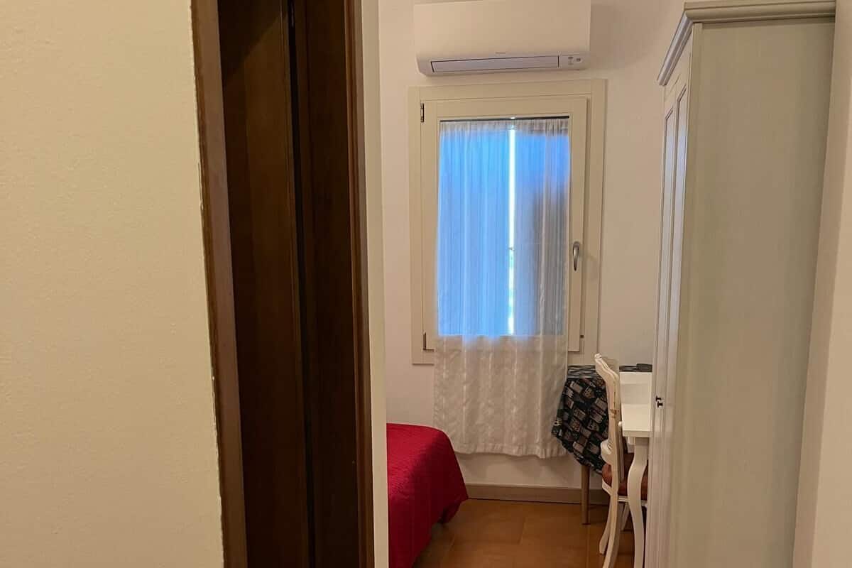 Un couloir étroit avec un lit, une table et une armoire.