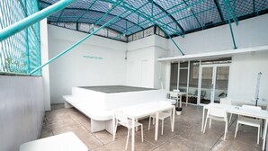 A modern, minimalist indoor space with a high ceiling, white walls, and a glass door leading to an outdoor area. - Bobopod Paskal, Bandung (Bandung)
