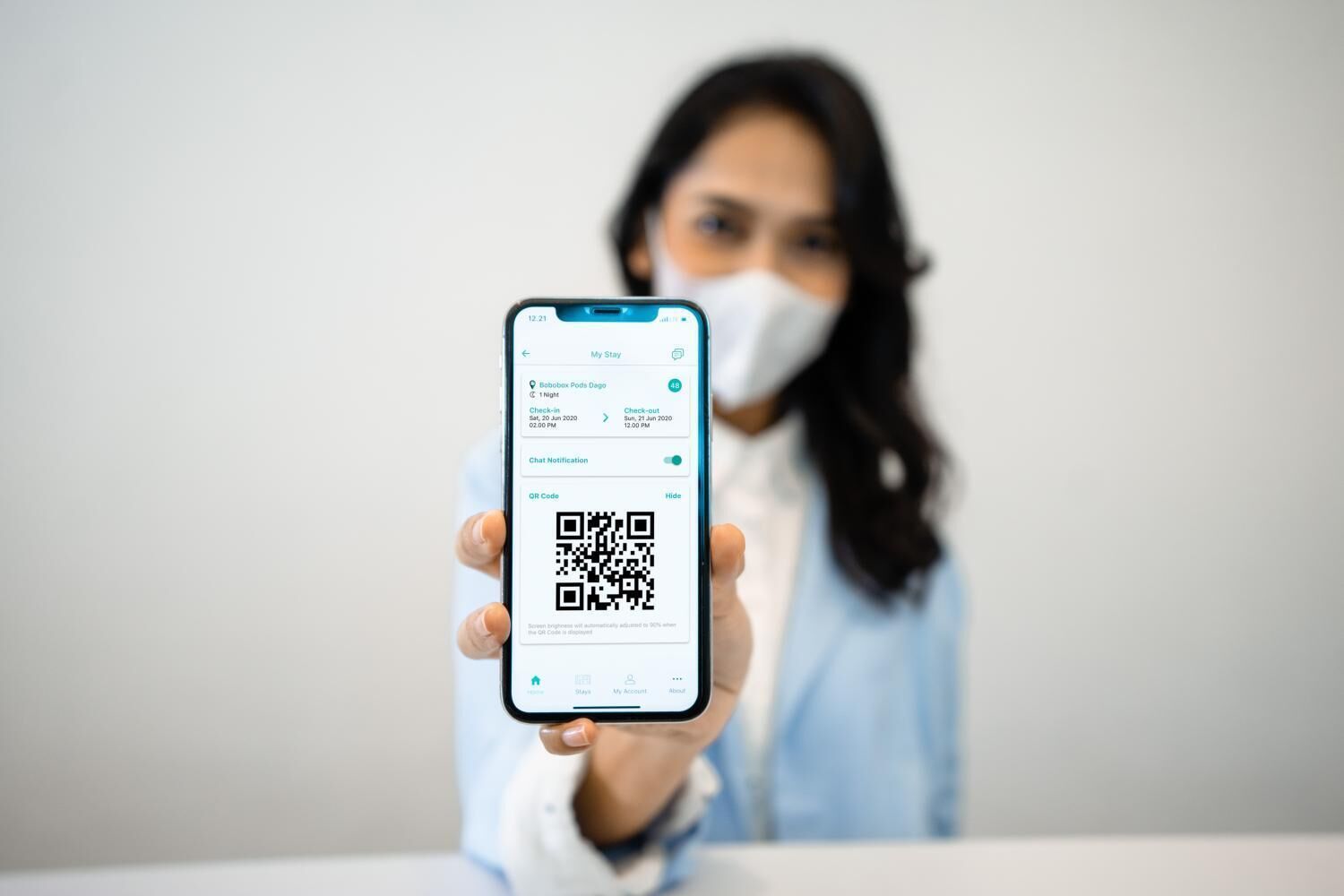 Una persona sosteniendo un teléfono inteligente que muestra un código QR y una notificación de registro en un hotel.