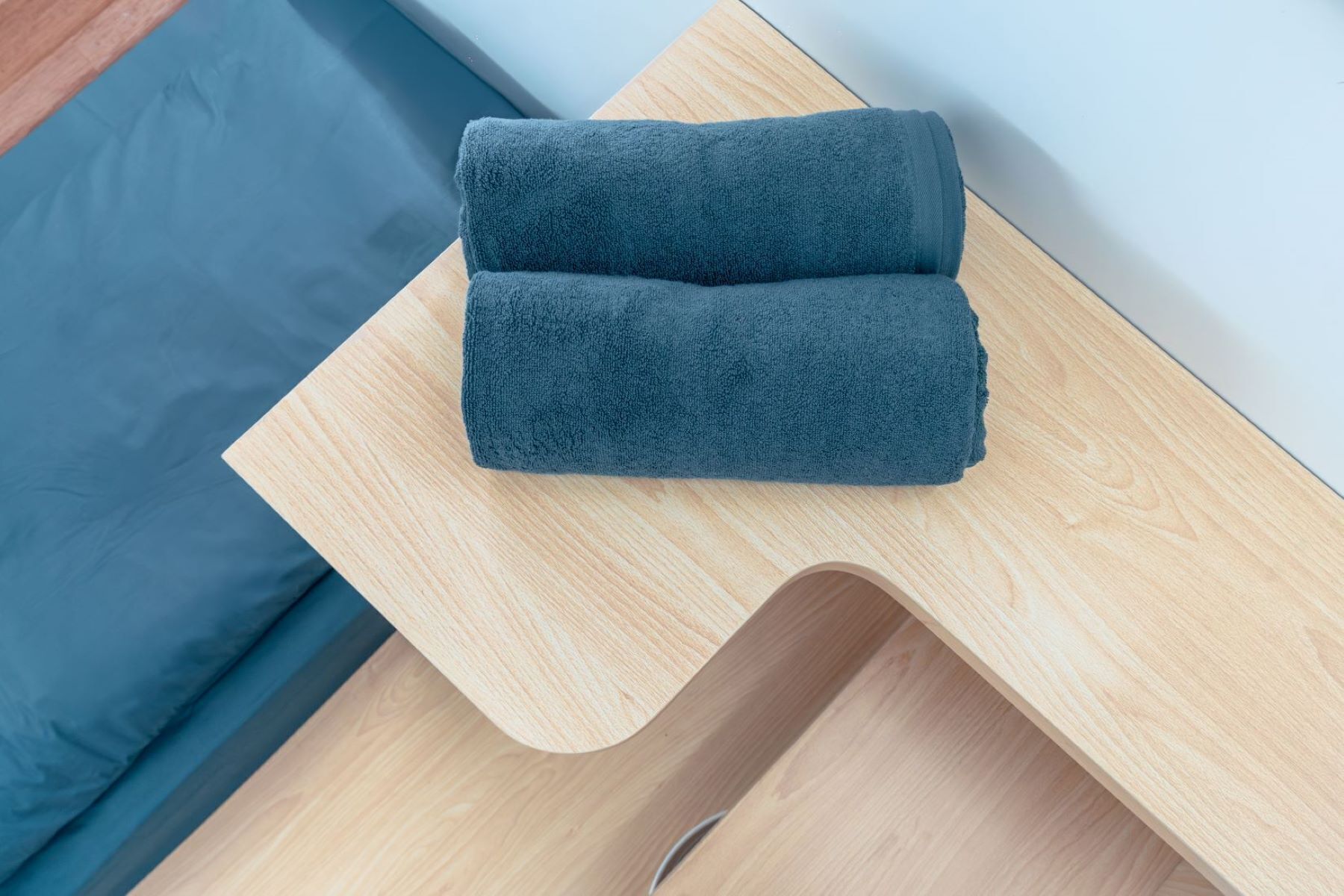 A neatly folded dark blue towel on a wooden side table.
