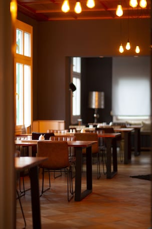 A restaurant with wooden tables and chairs, pendant lighting, and a view of the street.