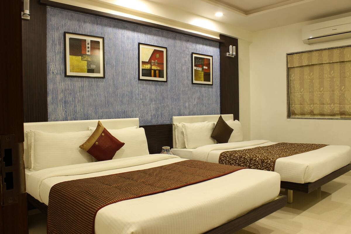 Ein Hotelzimmer mit zwei Betten, einem großen Spiegel und gerahmten Kunstwerken an der Wand.