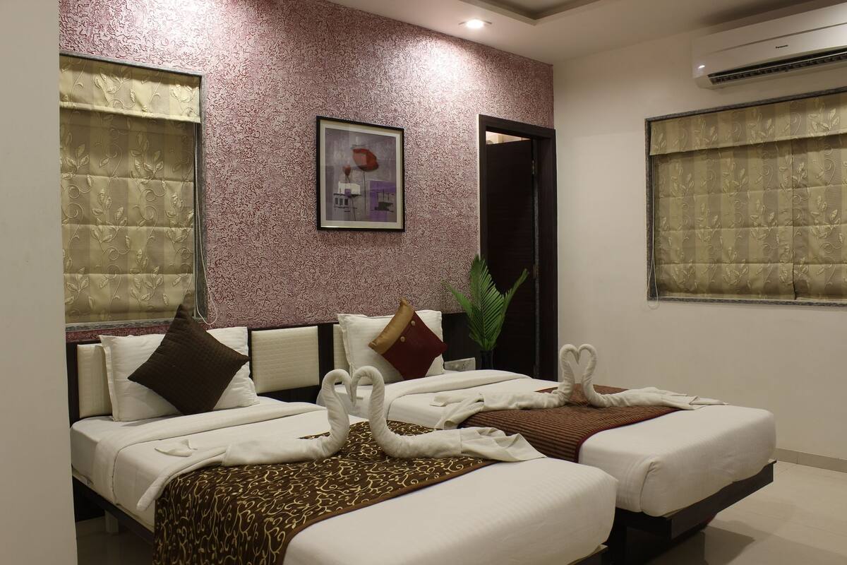 Ein Hotelzimmer mit zwei Betten, einem gerahmten Bild an der Wand und einem Blumentopf.