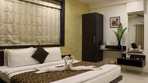 Una habitación de hotel con cama, armario, tocador con espejo y planta en maceta.