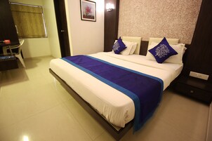 A neatly made bed with a blue and white bedspread, two pillows with blue floral designs, and a wall with a floral wallpaper pattern.