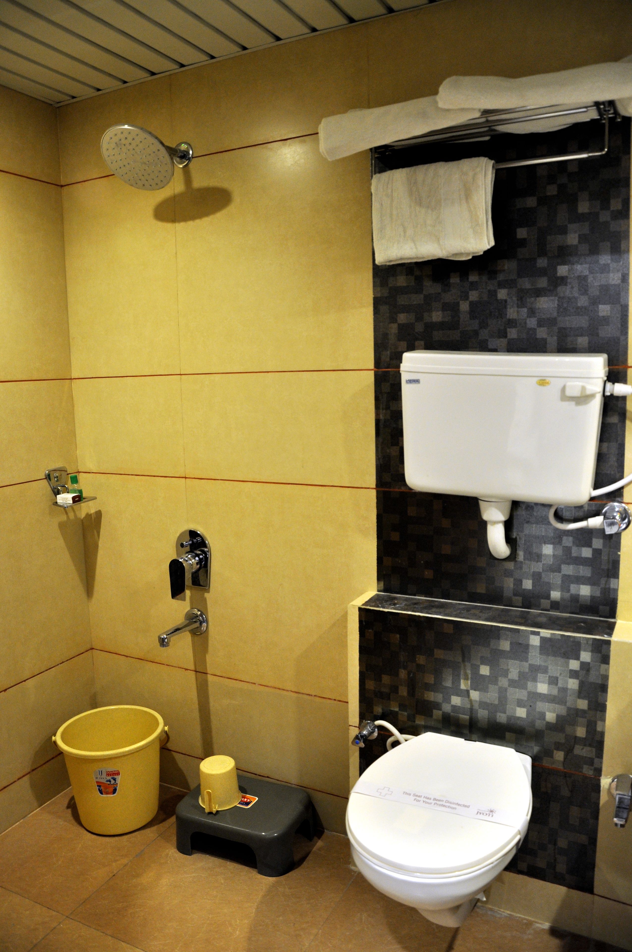 A bathroom with a shower, toilet, and a small step stool.