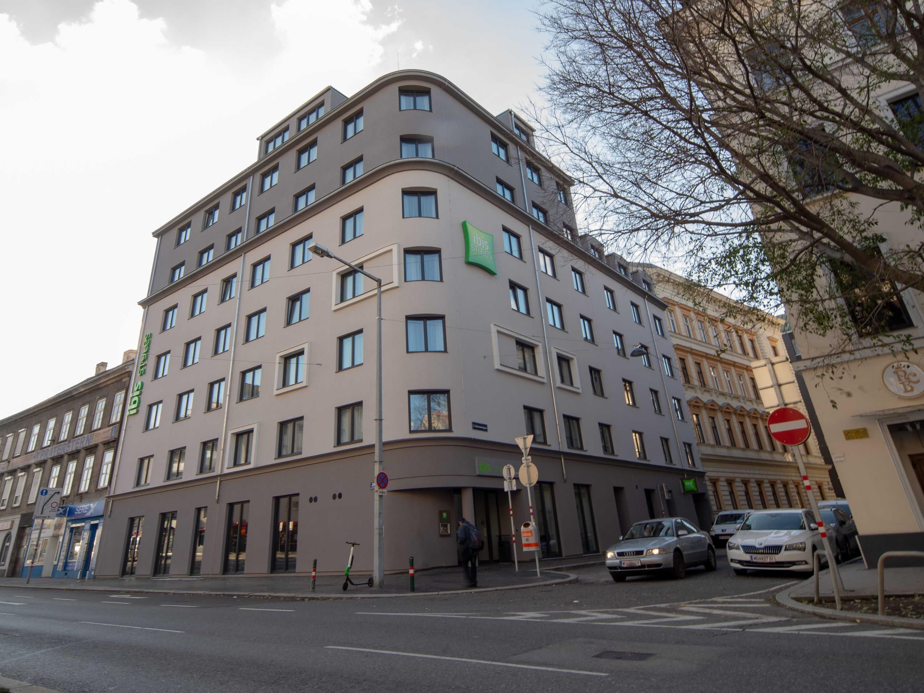 Un hotel de varios pisos con fachada curva, múltiples ventanas y un letrero que dice 'ibis stores'.