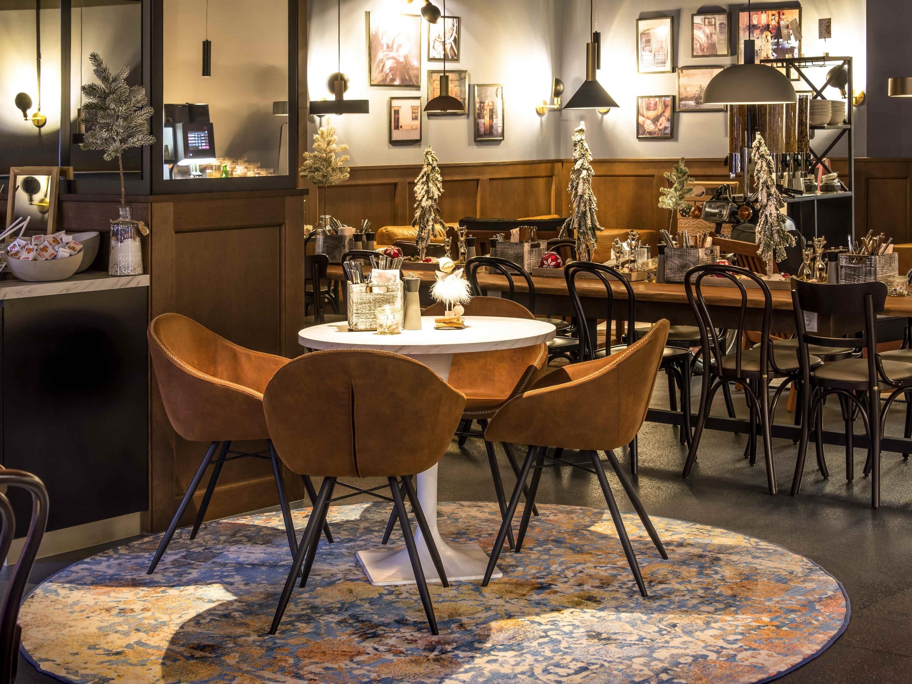 A restaurant with round tables, brown chairs, and a patterned carpet.