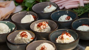 Bowls of dip with red chili flakes, surrounded by sliced meats and fresh vegetables. - ibis Styles Wien Messe Prater (Vienna)