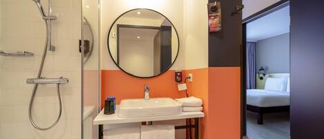 A modern bathroom with a shower, sink, and mirror.