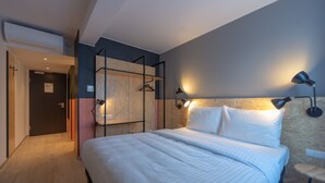 A modern hotel room with a large bed, a wooden wardrobe, and a desk with a chair. - ibis Styles Wien Messe Prater (Vienna)