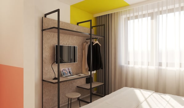 Una habitación de hotel moderna con literas, un escritorio con una computadora portátil, un televisor y un armario.