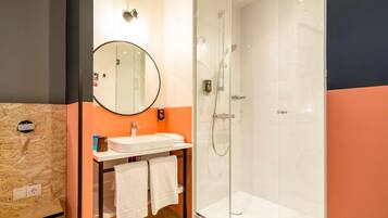 Une salle de bain moderne avec une douche à parois de verre, un miroir rond et un lavabo doté d’un porte-serviettes.