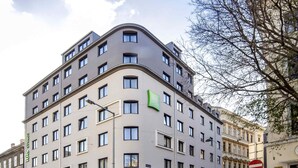 A multi-story hotel with a modern design, featuring a prominent green logo on the facade. - ibis Styles Wien Messe Prater (Vienna)