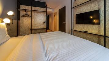 Una camera d'albergo moderna con un grande letto, una TV a muro e pannelli in legno sulle pareti.