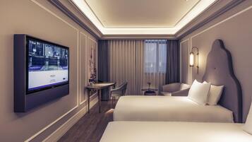 A hotel room with a large bed, a desk, a chair, a TV, and a window with curtains.