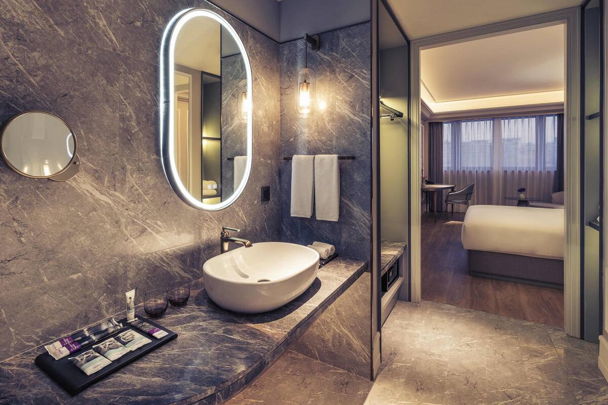 Een moderne badkamer met een grote, ovale spiegel, een wastafel en een meubel met toiletartikelen.