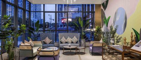 A spacious lobby with large windows, a modern chandelier, and a variety of seating arrangements.