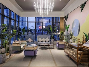 A spacious lobby with large windows, a modern chandelier, and a variety of seating arrangements.