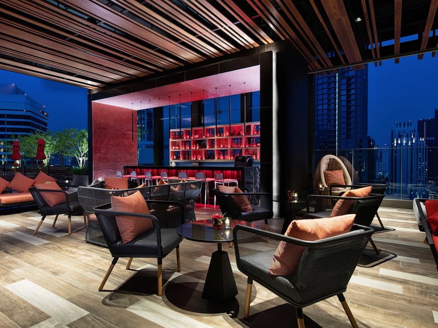 Un área de estar moderna con asientos y bar, con vista a la ciudad.