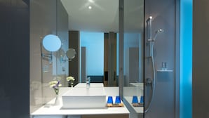 Een moderne badkamer met een grote spiegel, een witte wastafel en een douche.