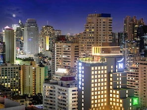 Un hotel de gran altura con varios pisos, un llamativo letrero de 'NOVOMATIC' y una terraza en la azotea.