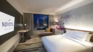 Una habitación de hotel con cama, escritorio, silla, televisor y vistas a la ciudad.
