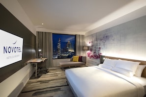 Una habitación de hotel con cama, escritorio, silla, televisor y vistas a la ciudad.