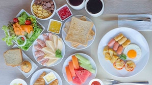 Een tafel met diverse ontbijtartikelen, zoals brood, eieren, ham en groenten.