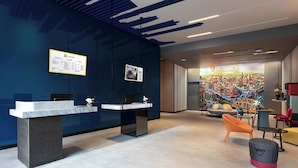 Un área de recepción moderna con dos mostradores, un mural y asientos contemporáneos.