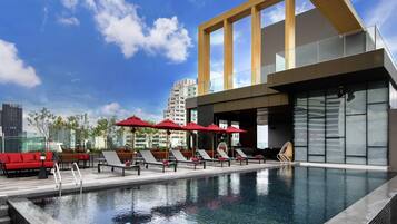 Una piscina al aire libre, sombrillas, tumbonas
