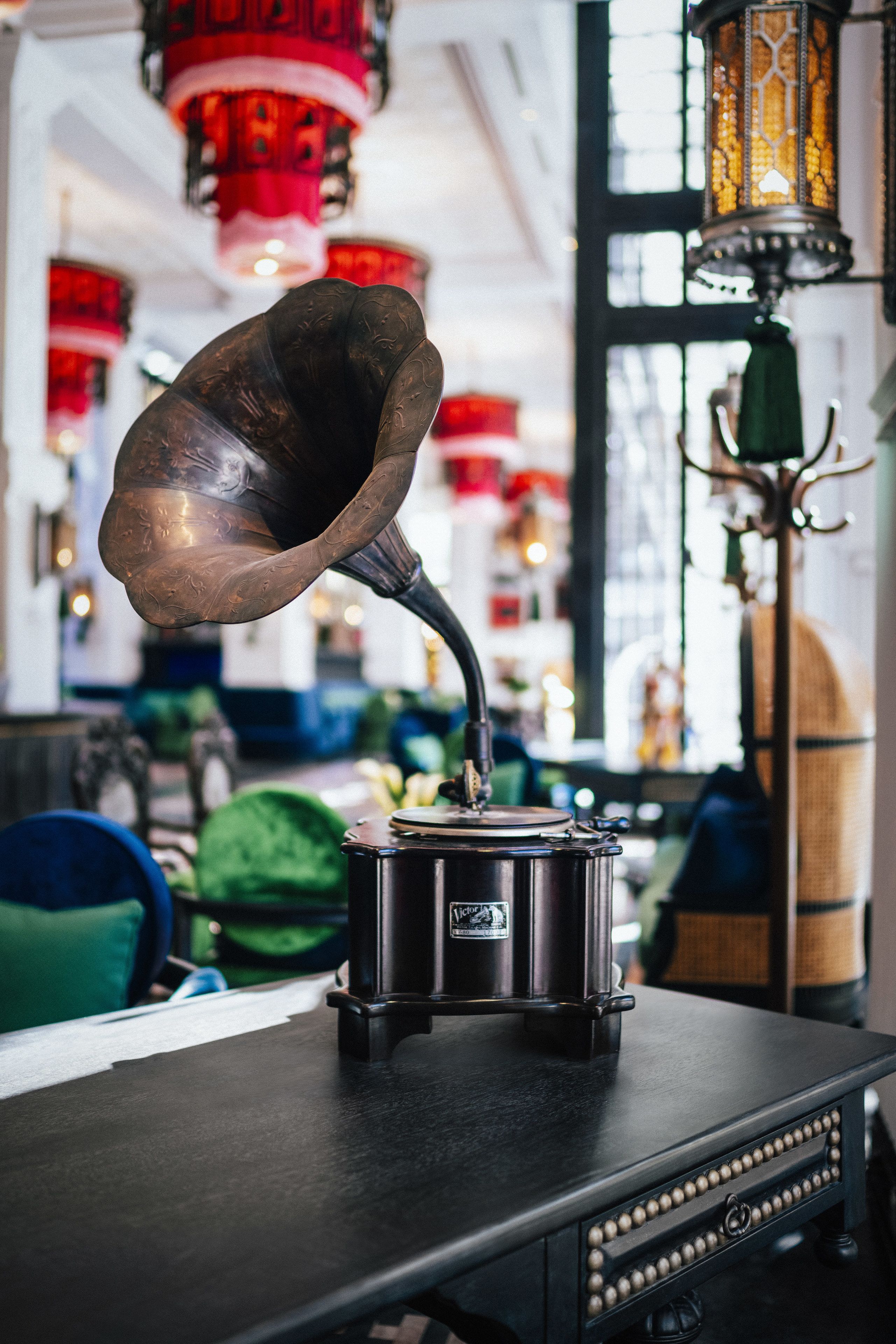 A gramophone on a table with a decorative lamp in the background.