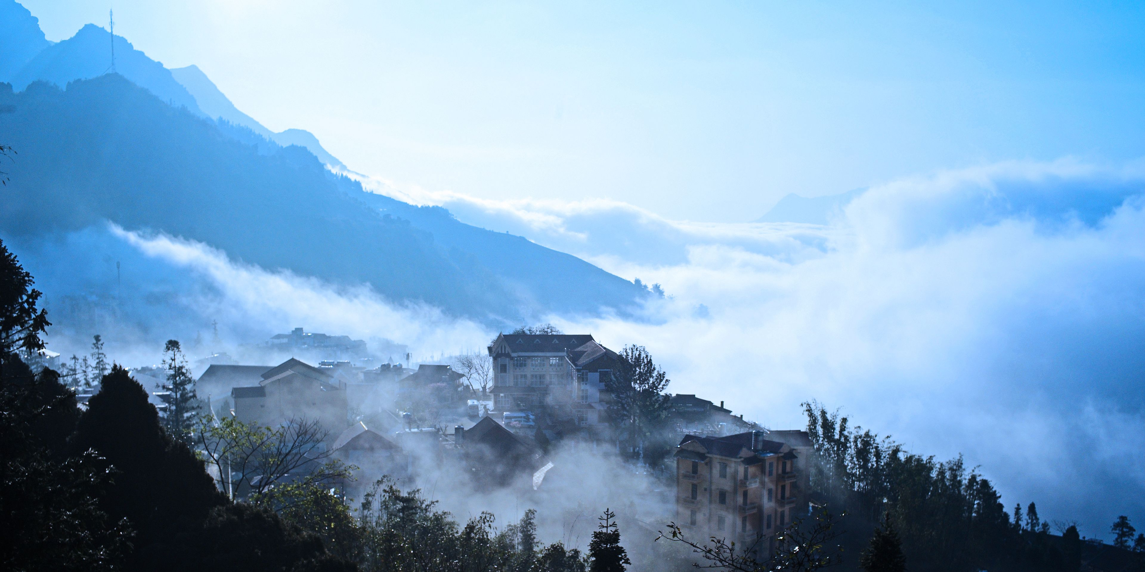 Un pueblo de montaña con edificios ubicados entre las nubes.